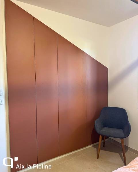 Dressing sur mesure avec des rangements en sous pente en teinte terracotta à Aix La Pioline