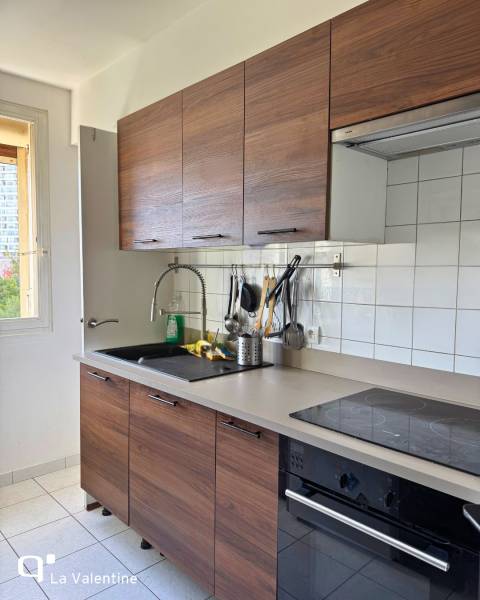 Cuisine sur-mesure avec façades en bois foncé et plan de travail beige à Marseille 13009