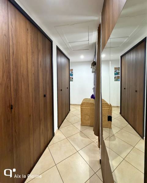 Couloir aménagé avec des portes de placards pliantes en bois foncé avec miroir et poignées noires à Aix