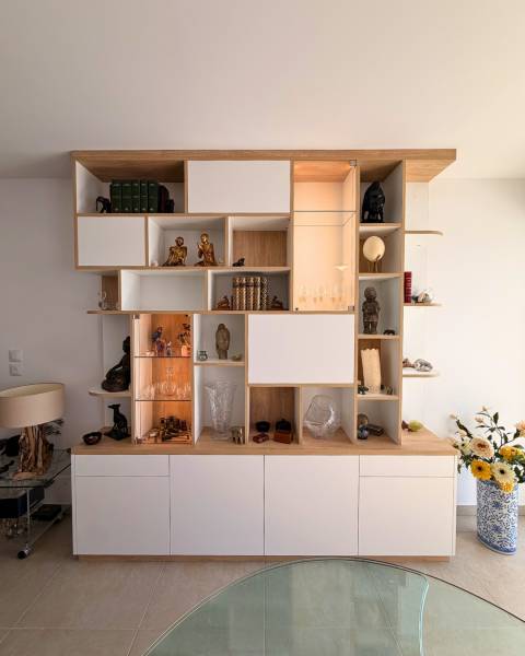 Aménagement sur mesure d'une bibliothèque bois et blanc avec des niches ouvertes et des vitrines éclairées à Aix en Provence