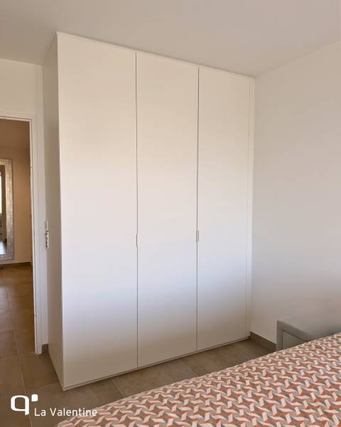 Aménagement d'un dressing sur mesure à Marseille avec portes battantes blanches et des espaces de rangement